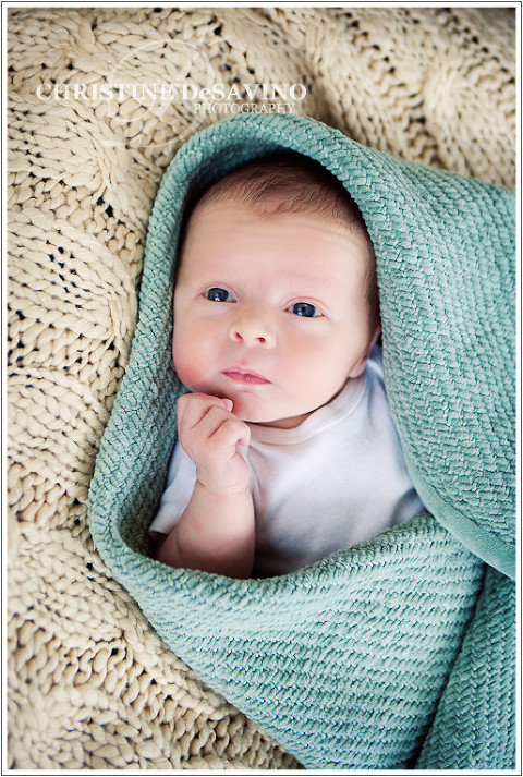 Photograph of a beautiful newborn boy under a turquoise blanket.
