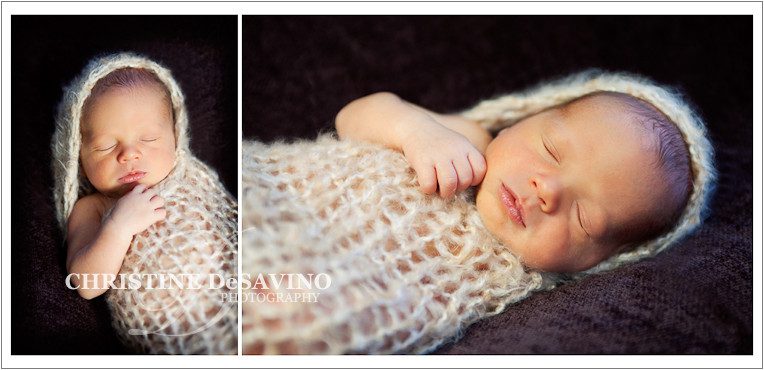 newborn baby boy sleeps in peanut wrap on brown blanket
