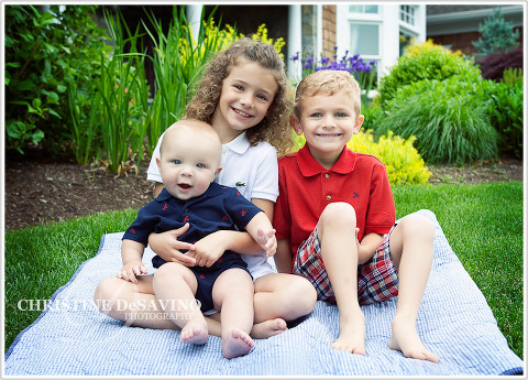 Adorable family on a blanket on the lawn in front of a beautiful home
