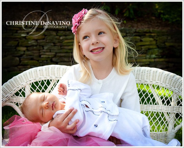 Beautiful blonde girl holding newborn baby brother.
