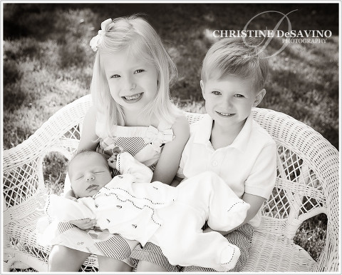 Adorable sister and brother holding their newborn baby brother.