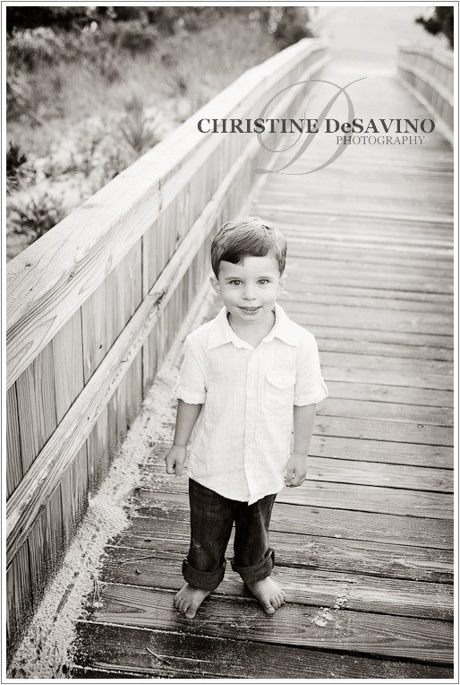 Black and white image of young boy on the boardwalk at the beach