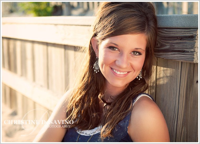 Beautiful teen girl sitting on boardwalk at sunset