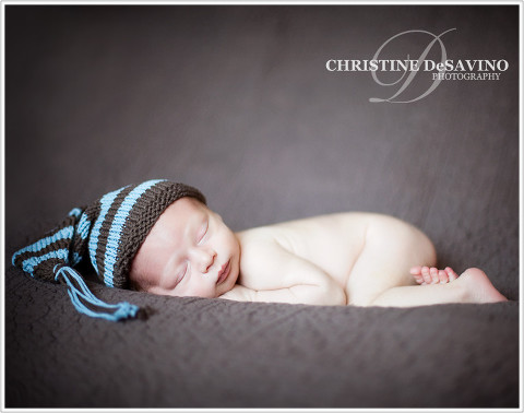 Beautiful newborn boy with knit hat lying on brown blanket