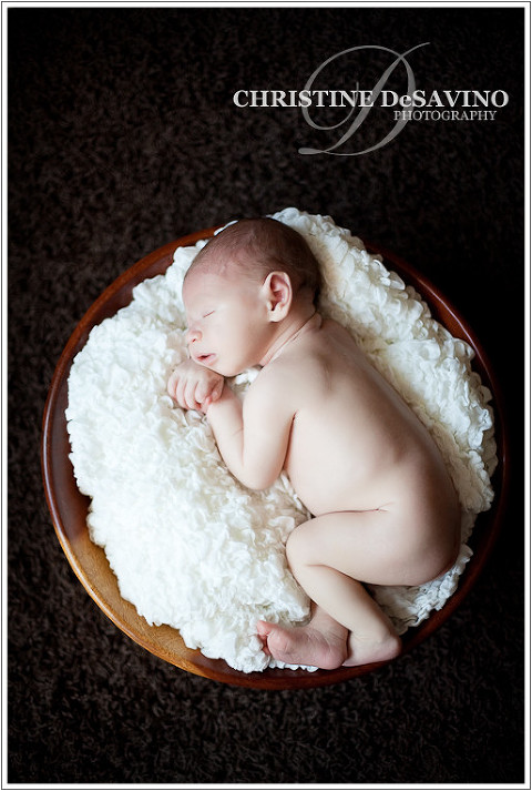 Image of newborn boy in wooden bowl with soft blanket