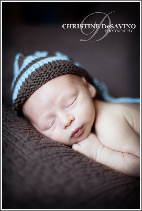 Precious newborn boy with knit hat sleeping on blanket