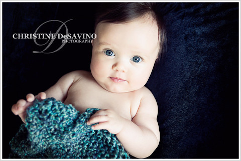 Blue-eyed baby on black with green knit - NY Baby Photographer