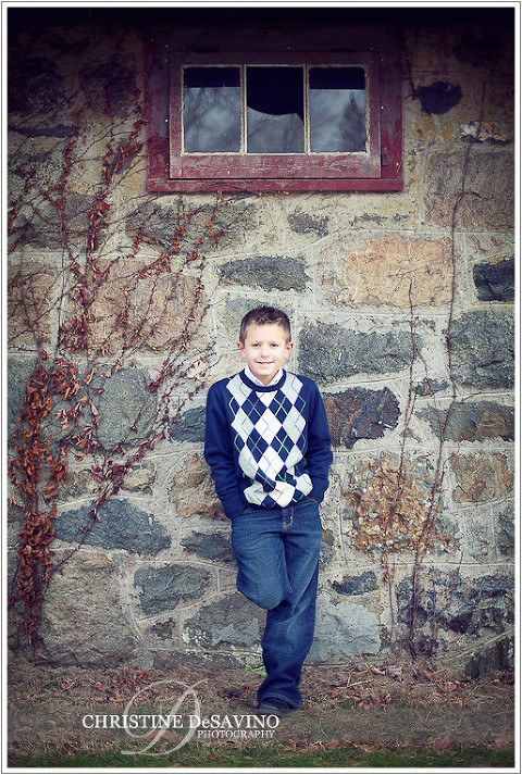 Boy leans against beautiful stone wall with broken window - NY Children's Photographe