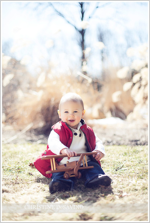 Boy in red vest holding wooden airplane - NJ Child Photographer