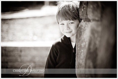 Black and white of boy peaking from behind a stone wall - NJ Child Photographer