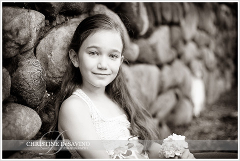 Black and whit of girl sitting against stone wall - NJ Child Photographer